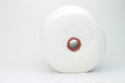 Close-up of pristine white, finely plied 100% cashmere yarn, showcasing its soft halo and subtle sheen on a neutral background.
