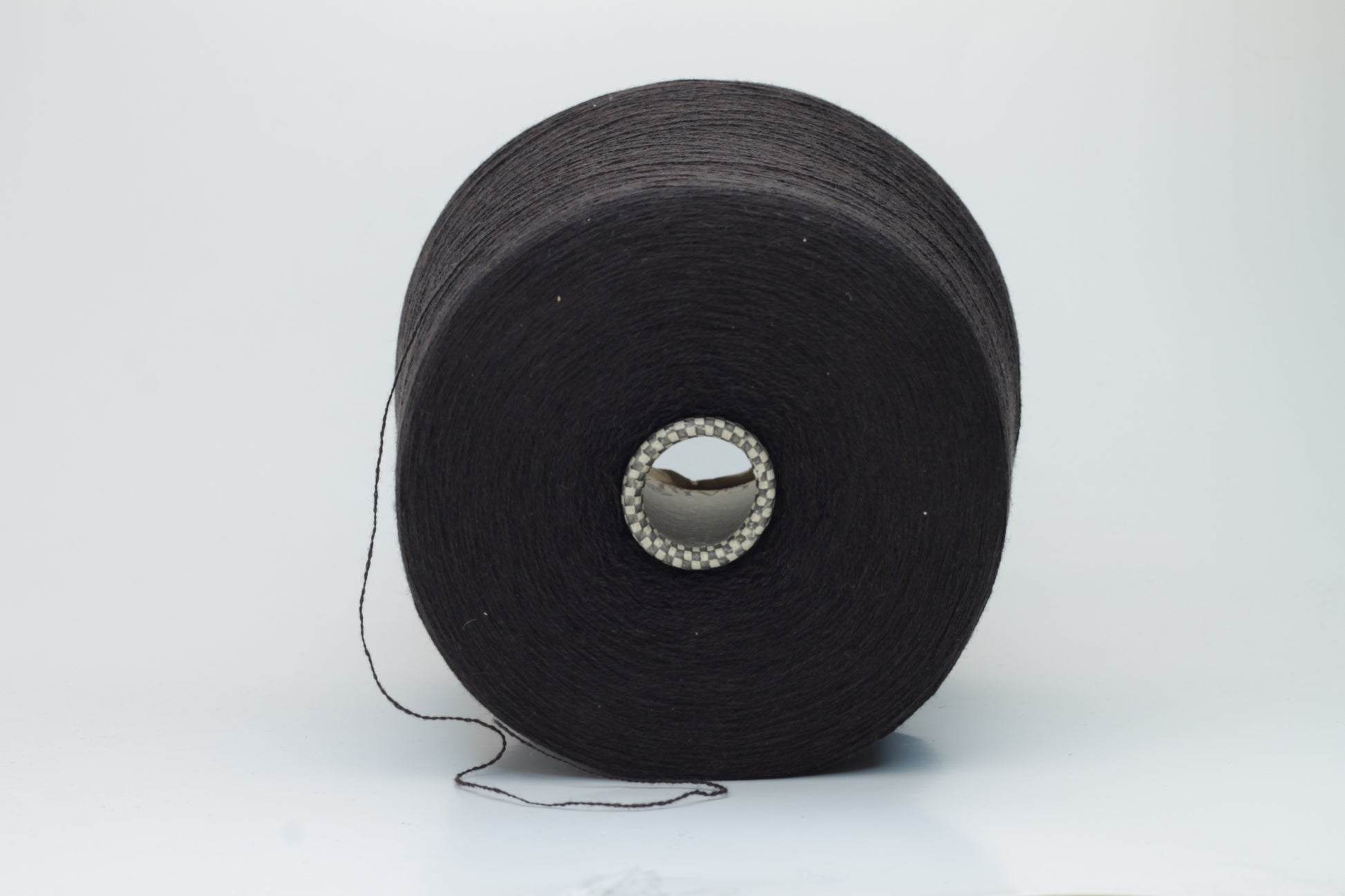 Close-up of a two-ply dark brown cashmere yarn, softly twisted with a subtle sheen, displaying its deep rich hue and delicate fuzziness, ready for luxury crafting.