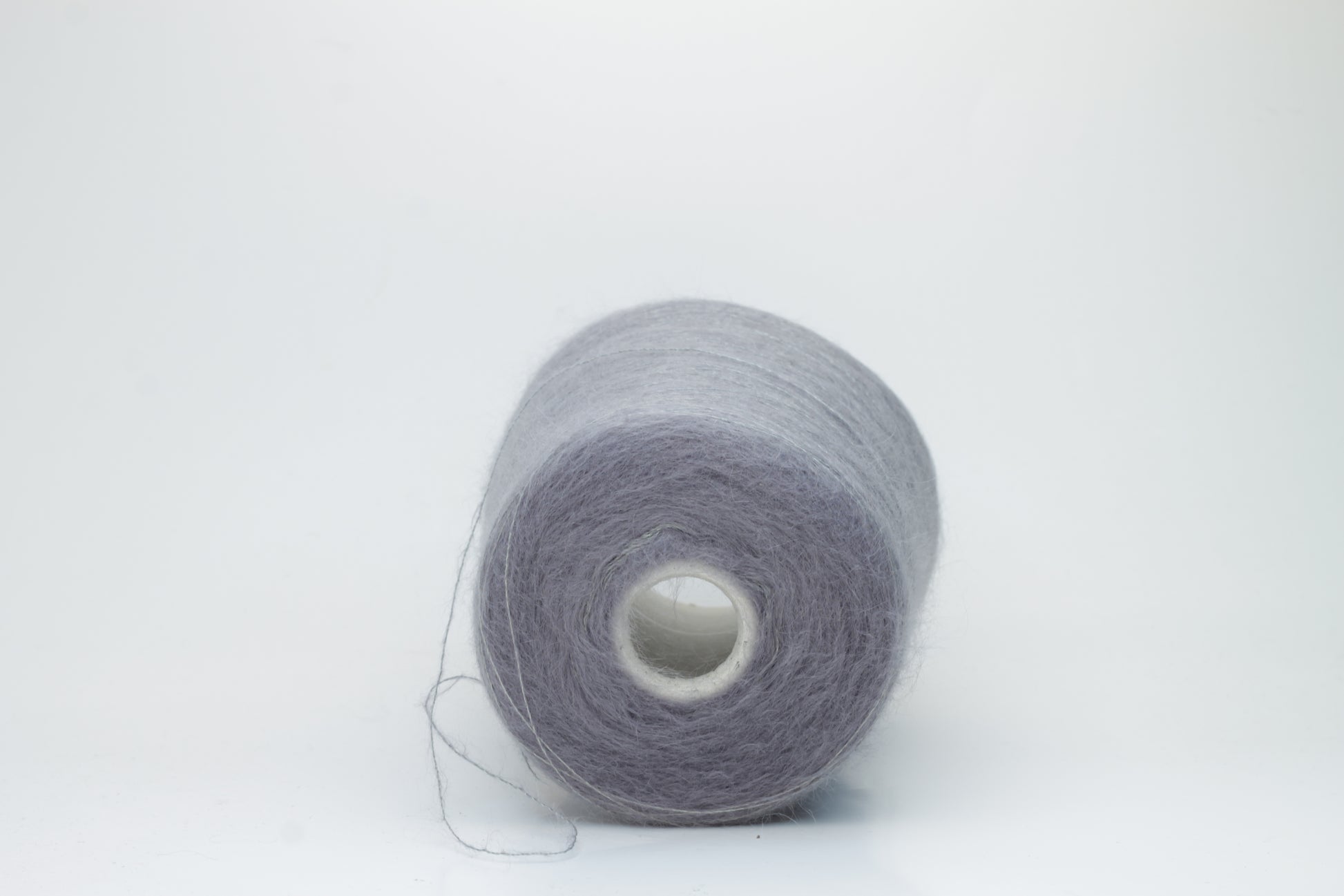 Close-up of fluffy Smog (Gray) kid mohair and silk blend yarn, subtly lustrous with a soft halo, gently twisted into a fine, delicate thread.