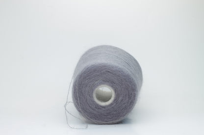 Close-up of fluffy Smog (Gray) kid mohair and silk blend yarn, subtly lustrous with a soft halo, gently twisted into a fine, delicate thread.