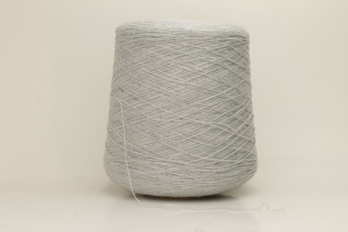 Close-up of a two-ply, fine gauge cashmere yarn in a soft, ethereal misty grey-blue hue with a subtle halo and gentle sheen.