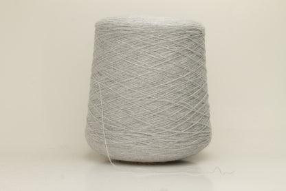 Close-up of a two-ply, fine gauge cashmere yarn in a soft, ethereal misty grey-blue hue with a subtle halo and gentle sheen.