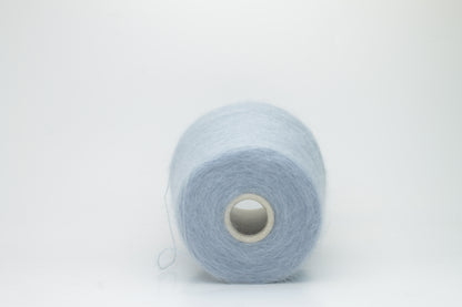 Close-up of fluffy Cielo kid mohair and silk blend yarn, subtly lustrous with a soft halo, gently twisted into a fine, delicate thread.