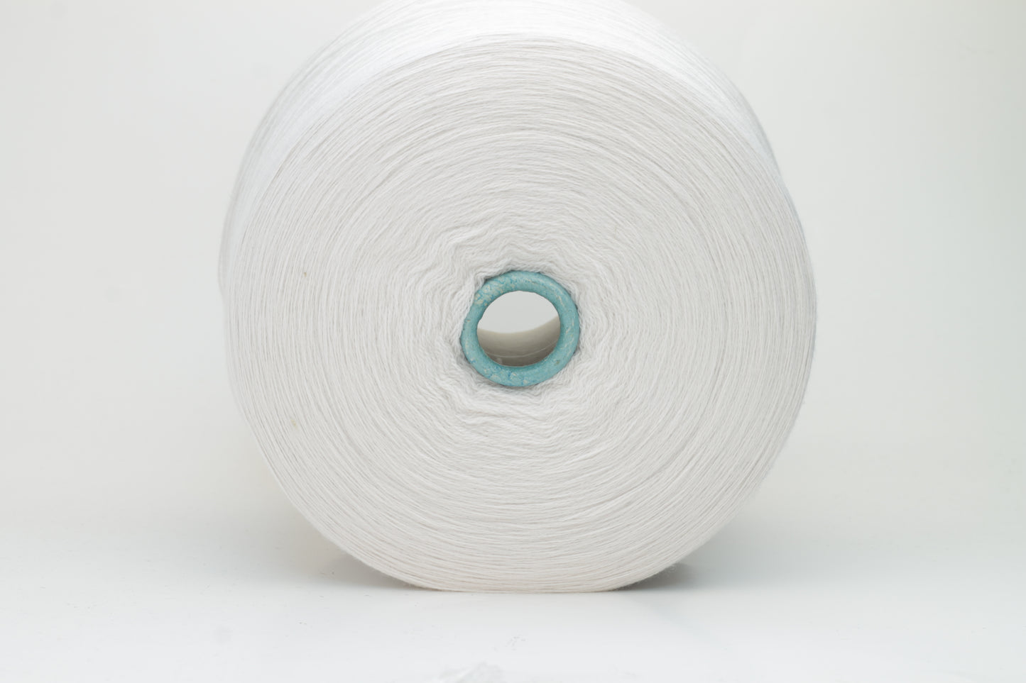 Close-up shot of creamy white Zegna Baruffa merino yarn, showcasing a dense, twisted ply structure and subtle sheen, with a fluffy texture inviting tactile exploration.