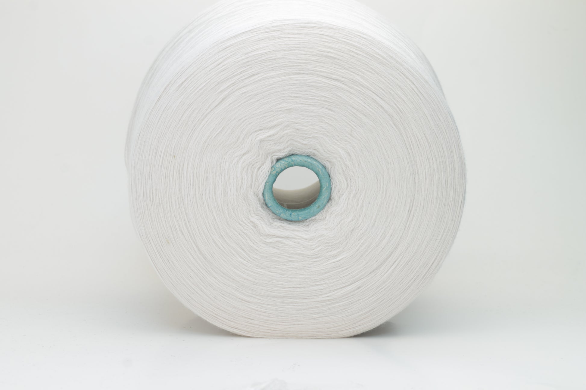 Close-up shot of creamy white Zegna Baruffa merino yarn, showcasing a dense, twisted ply structure and subtle sheen, with a fluffy texture inviting tactile exploration.