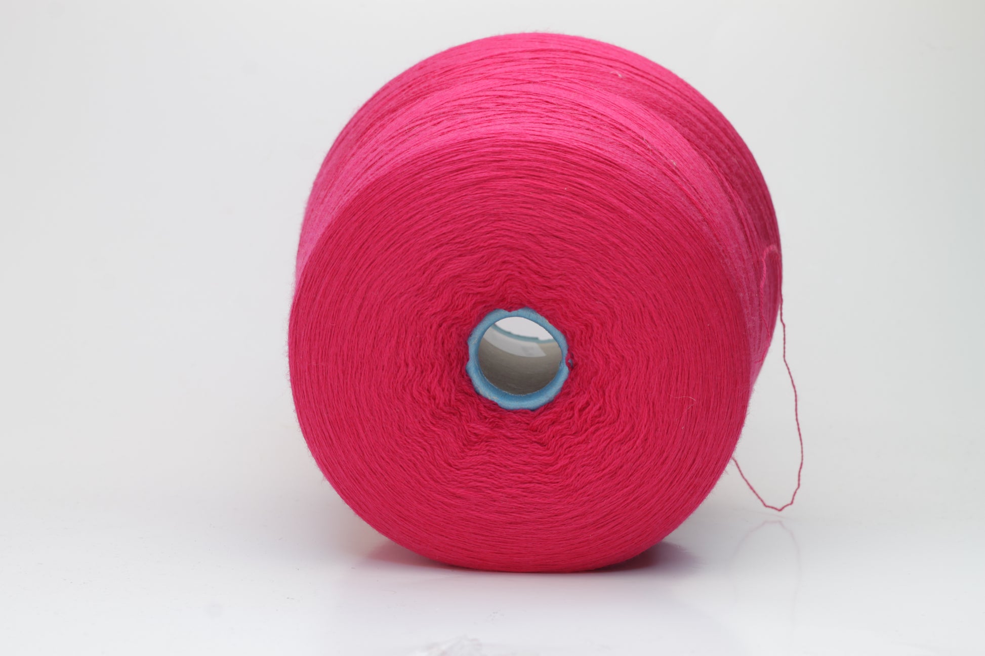 Close-up of vibrant fuchsia 100% merino yarn, showcasing a tight ply twist and a dense, fluffy texture with subtle sheen, perfect for intricate knit designs.