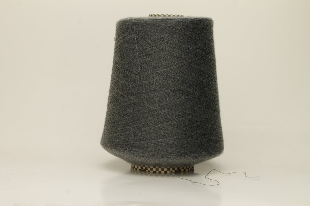 Close-up of a luxurious, finely spun two-ply cashmere silk blend yarn in a soft, elegant gray shade with a subtle sheen, showcasing its delicate texture.