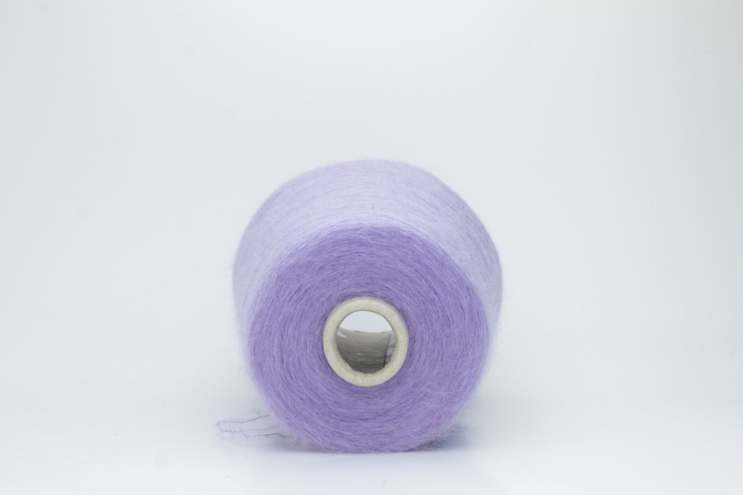Close-up of fluffy Lila kid mohair and silk blend yarn, subtly lustrous with a soft halo, gently twisted into a fine, delicate thread.