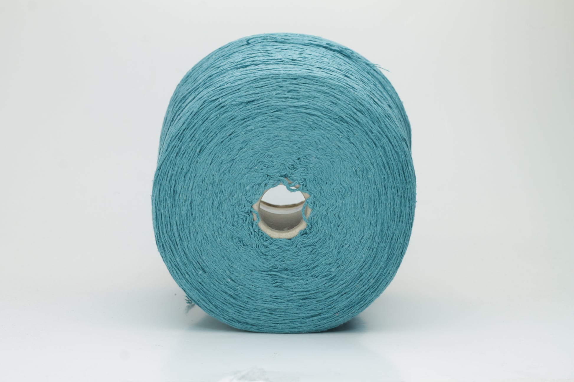 Close-up of a skein of deep petrol blue-green bourette silk yarn, showing its characteristic subtle slubs and matte texture, with a gentle, soft twist.