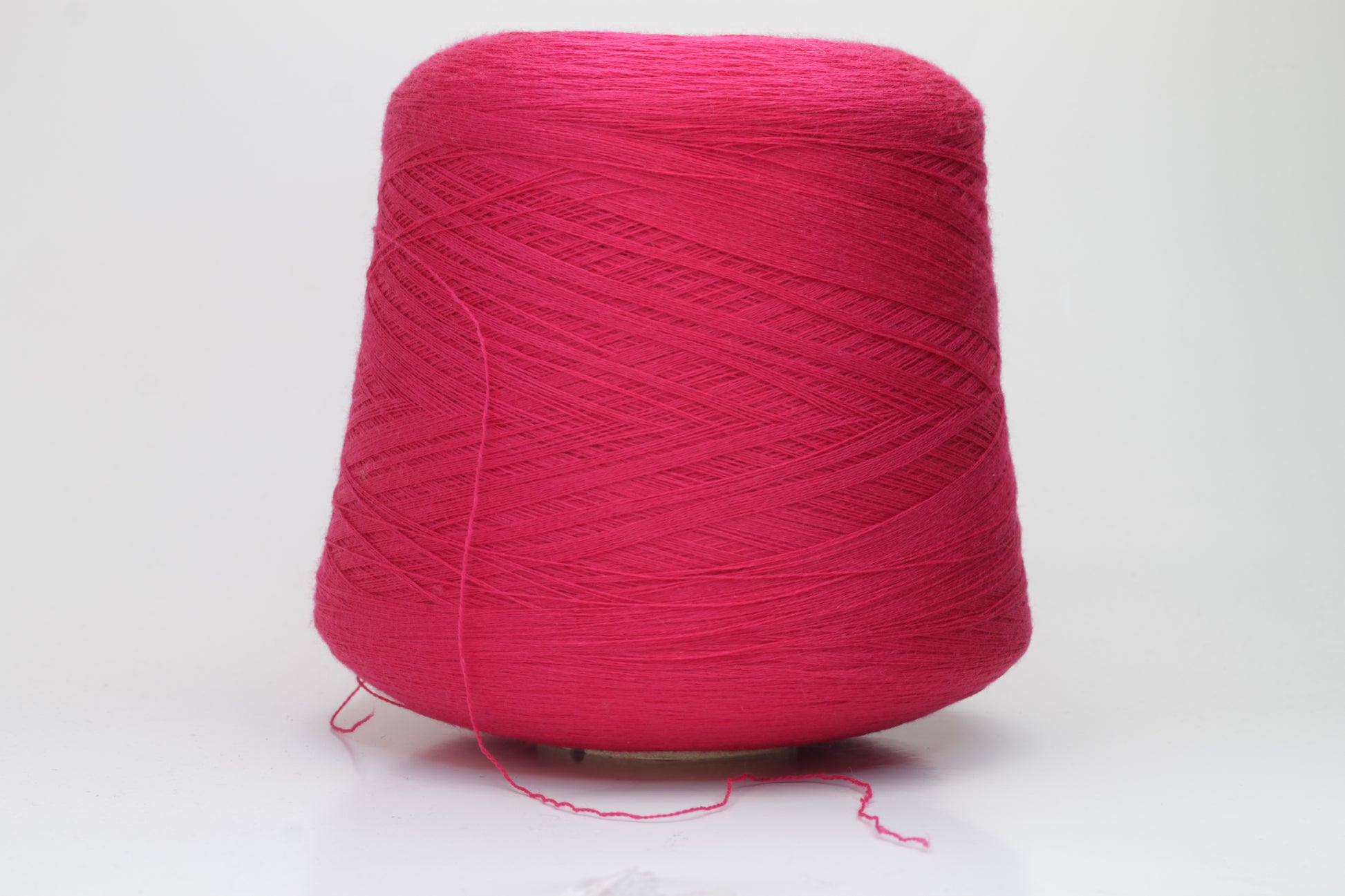 Close-up of vibrant fuchsia 100% merino yarn, showcasing a tight ply twist and a dense, fluffy texture with subtle sheen, perfect for intricate knit designs.