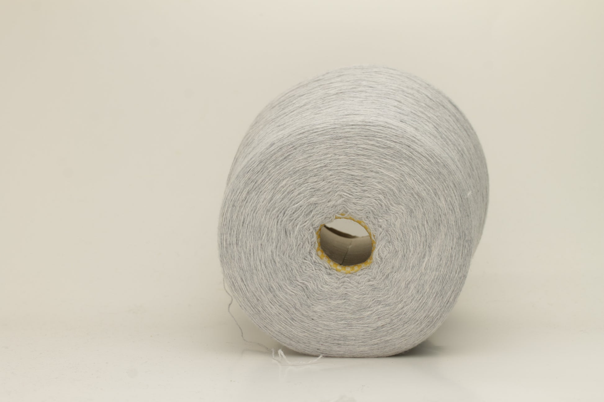 Close-up of a two-ply, fine gauge cashmere yarn in a soft, ethereal misty grey-blue hue with a subtle halo and gentle sheen.