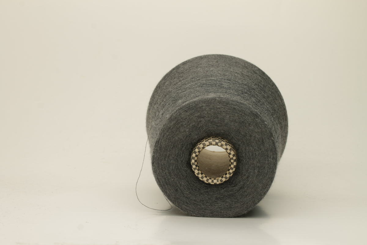 Close-up of a luxurious, finely spun two-ply cashmere silk blend yarn in a soft, elegant gray shade with a subtle sheen, showcasing its delicate texture.